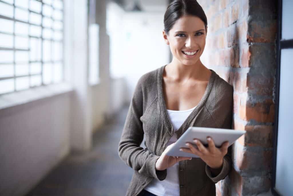 Standing smiling woman holding an iPad